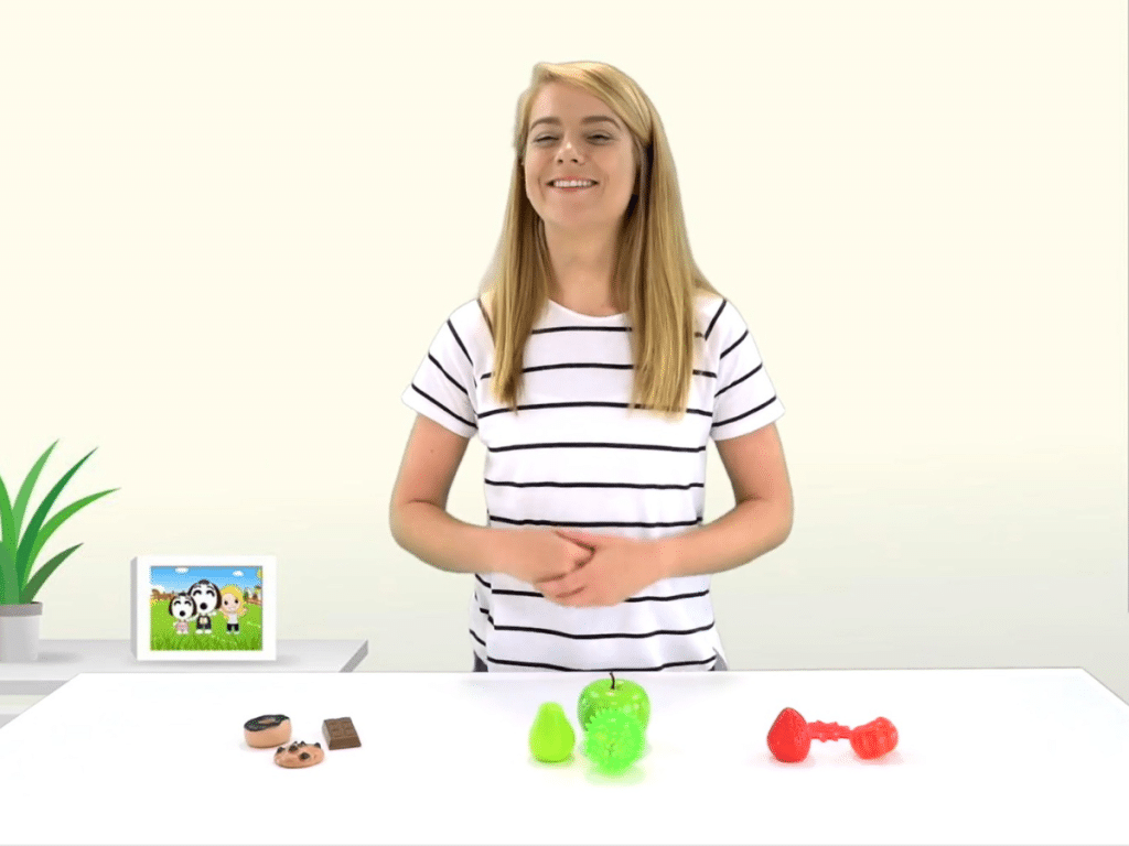 SHICHIDA at Home presenter Emma is laughing, and we see some toys sorted in colour on a table in front of her