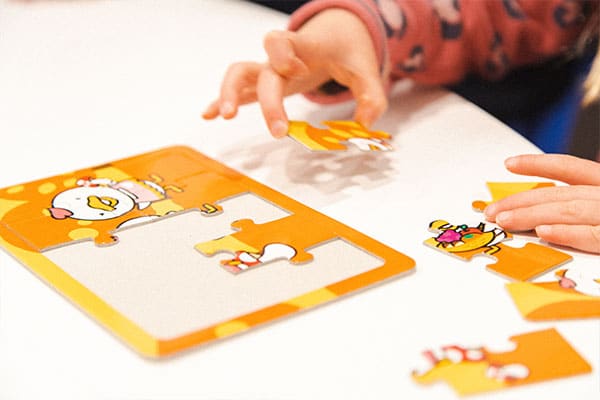 Children's Fine Motor Skills Activities and games, featuring the hands of a preschooler building a puzzle in a Shichida class