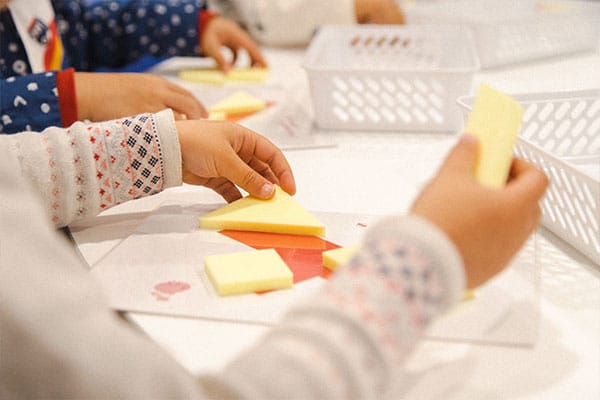 Problem Solving for Children activities and games, featuring preschoolers solving a 3D trangram puzzle challenge in a Shichida class