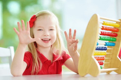 Young girl showing eight on her fingers, next to an abacus, a great example of numeracy in early childhood