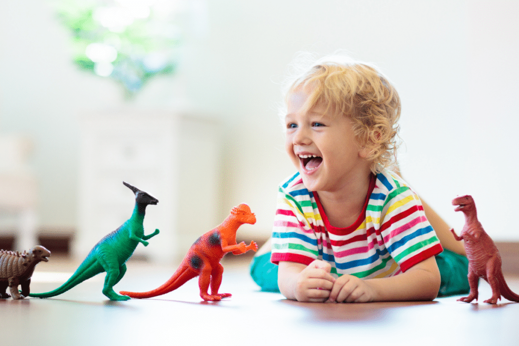 Learning Through Play: Types of Play Development, showing a young boy playing with dinosaurs