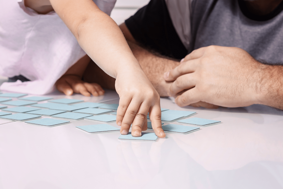 A young girl playing a memory match game with an adult male, in a demonstration of the importance of language and memory development