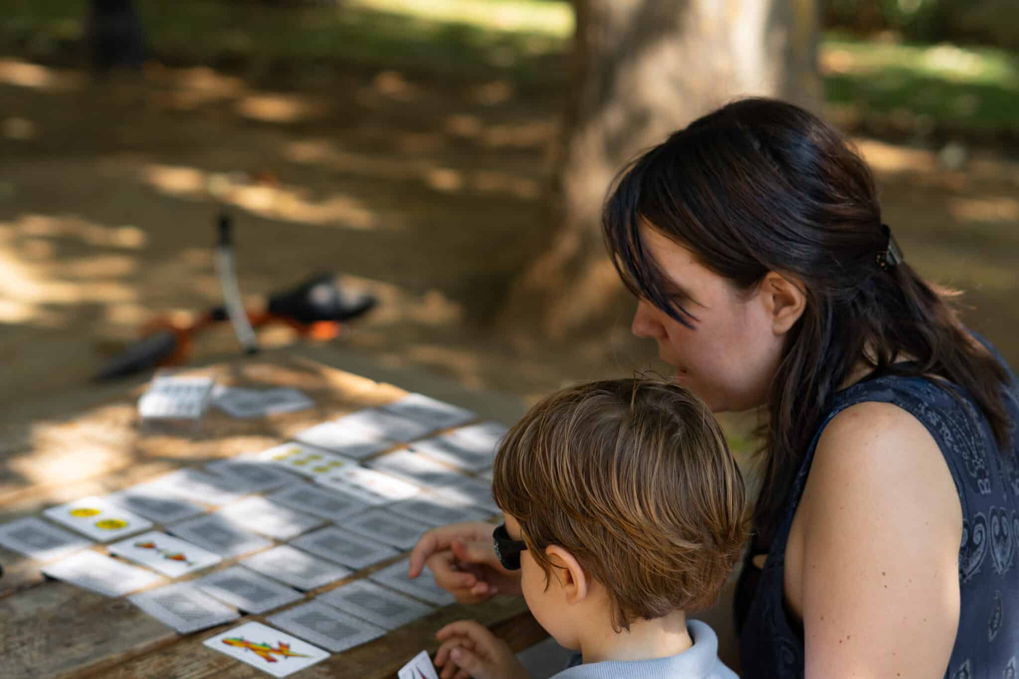 mum playing memory games cards in the park with her young child on a sunny day
