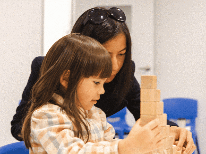 a woman and a girl playing with blocks