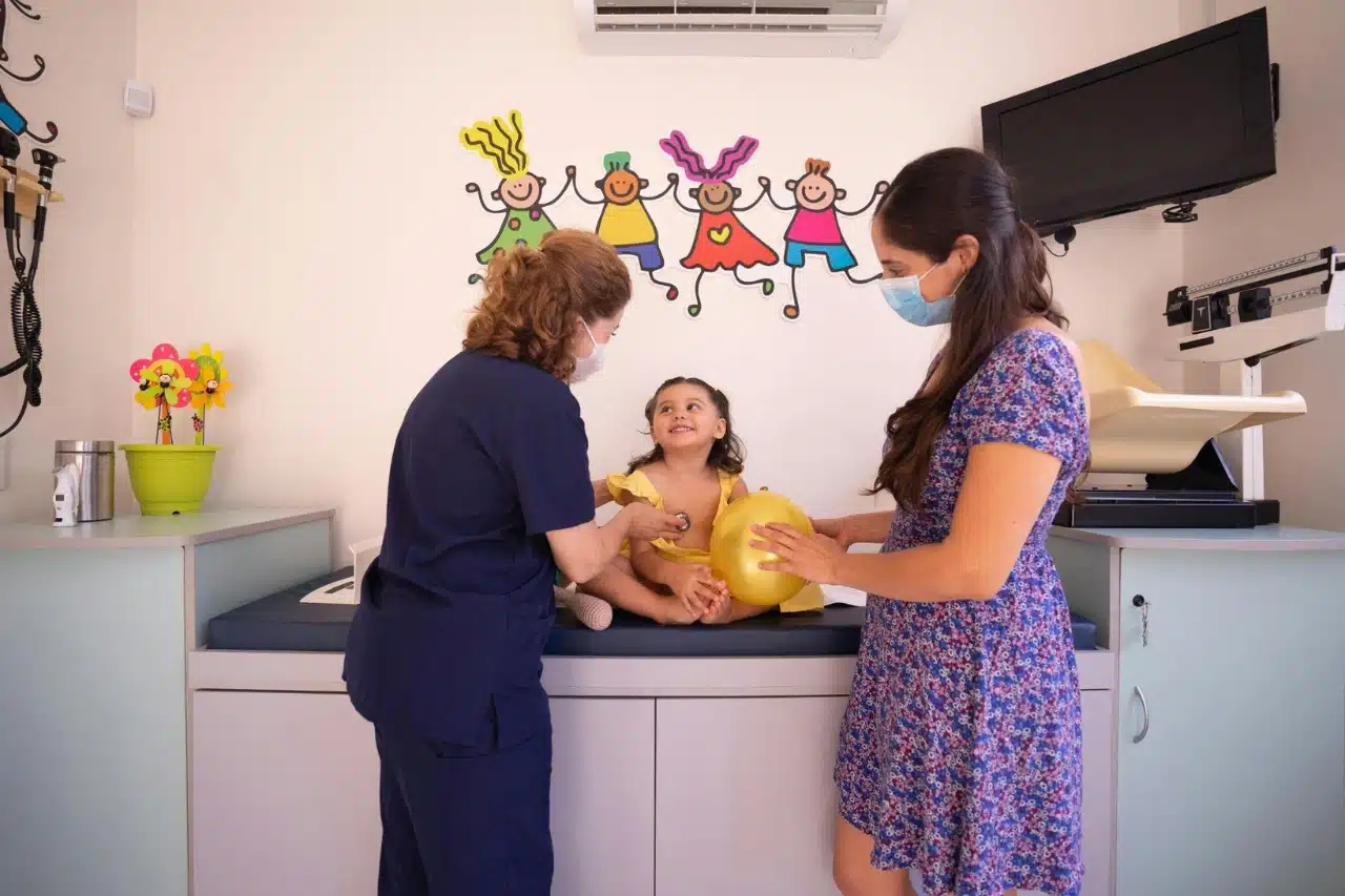 A woman in a hospital examines a child, focusing on their health and well-being during a medical check-up