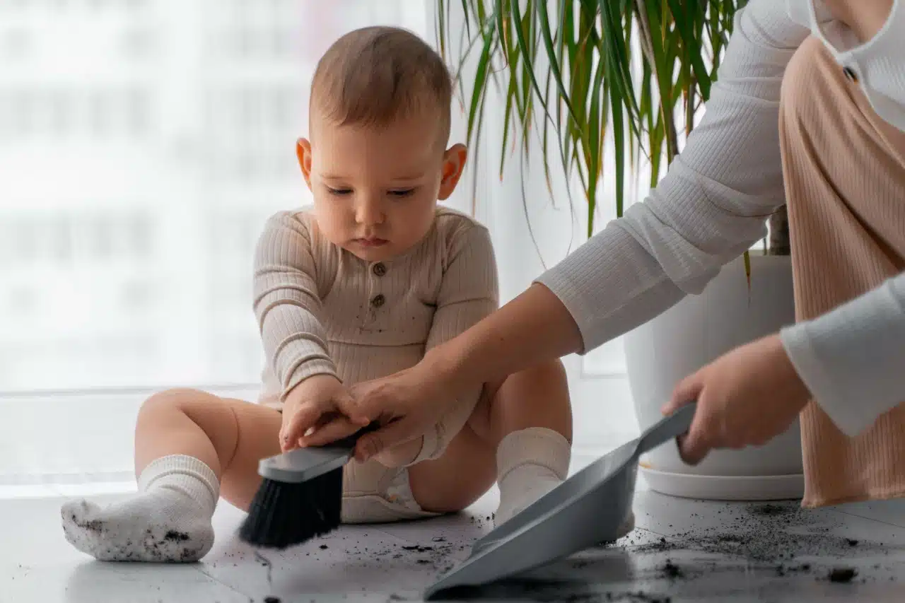 baby holding brush to help clean with mother