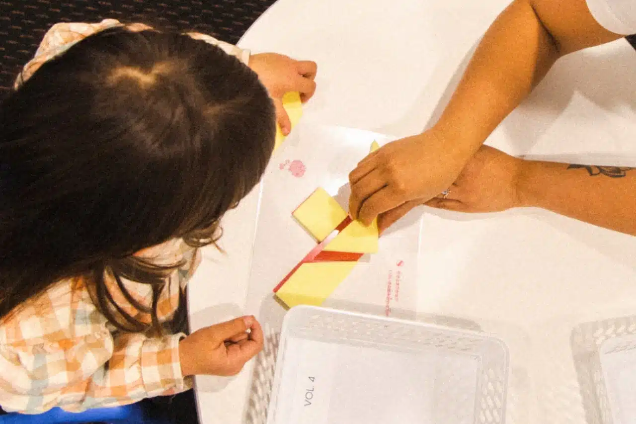 A woman and a child are engaged in crafting together at a table, surrounded by various art supplies