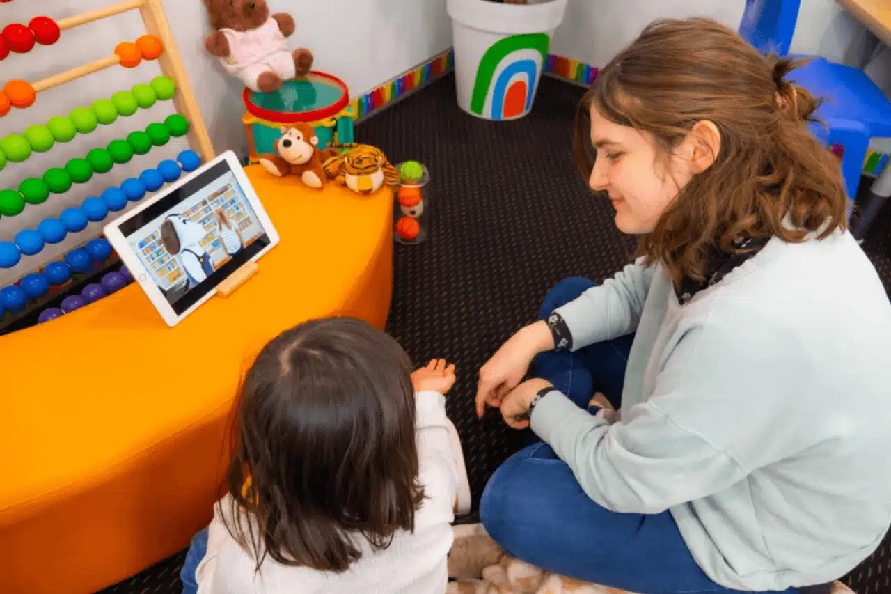 A woman and a child sitting together, focused on a tablet in front of them