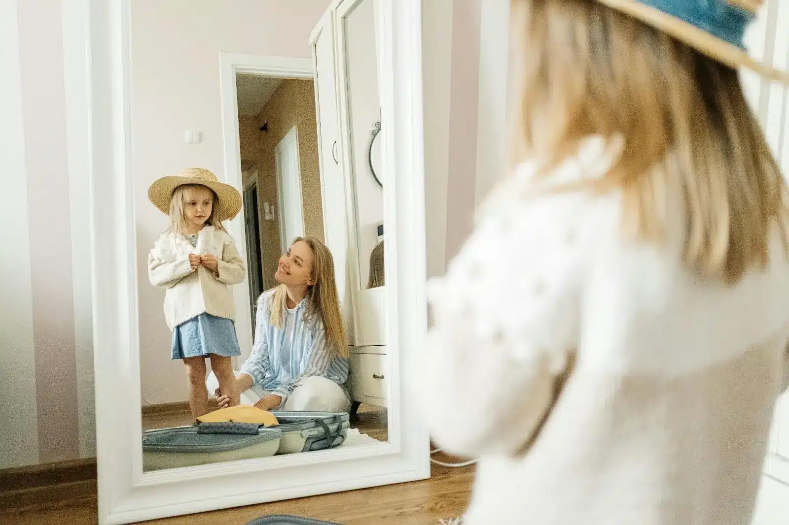 Decision Making for Kids: Mother and daughter in front of a mirror, with the daughter wearing a hat and the mother sitting on the floor smiling.
