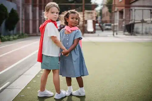 A young girl in a furry white jacket gently touches a boy's chin, and they are both smiling.