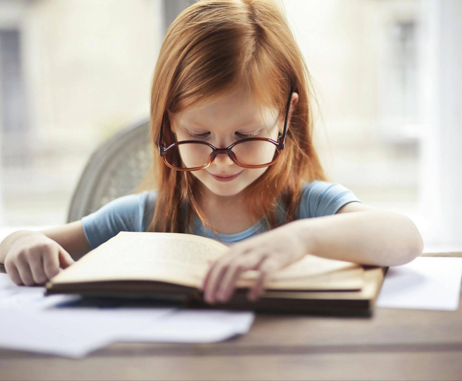 Speed reading for kids - Kid Girl with Eyeglasses reading a book