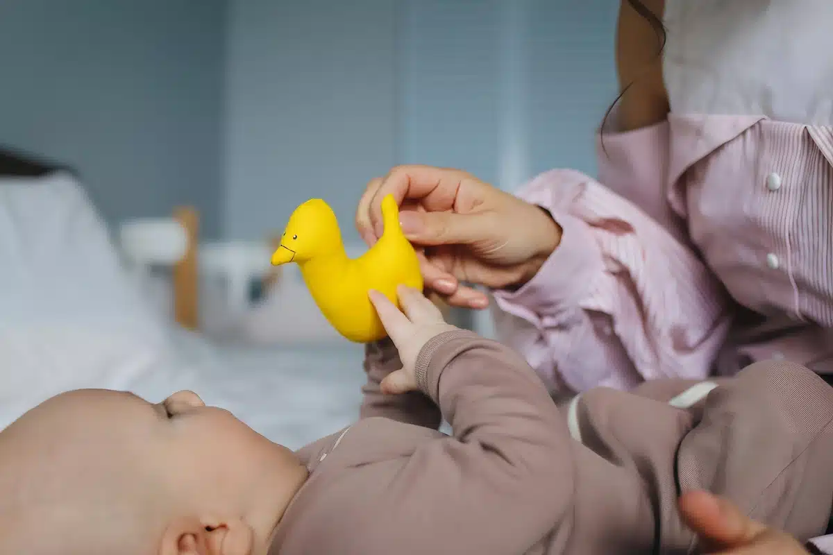A parent guiding their baby’s hand to touch textured toys