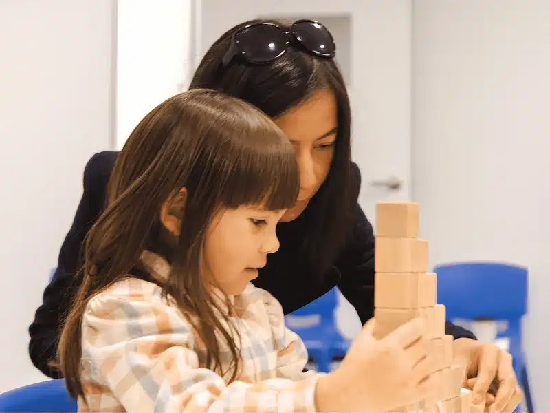 A preschooler plays a block challenge game alongside their parent