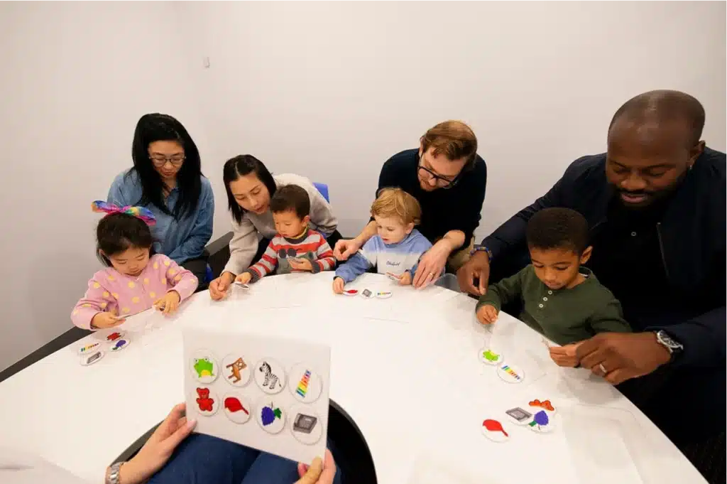 Preschoolers playing a visual memory game alongside their parents during a Shichida class