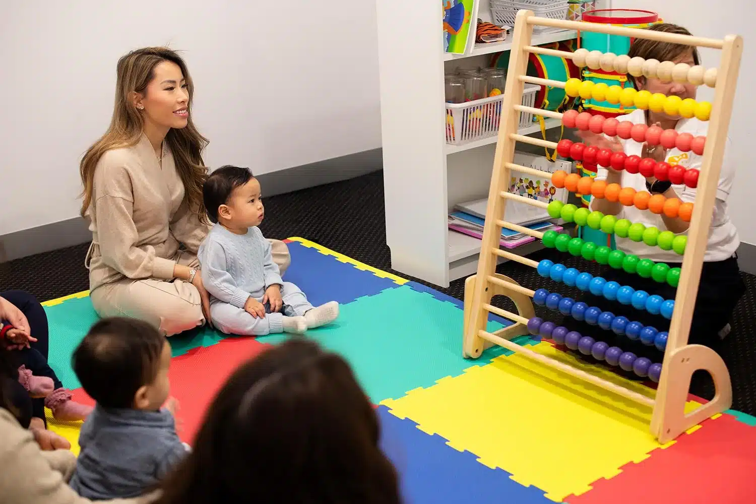 Baby watching a teacher count on a large colourful abacus